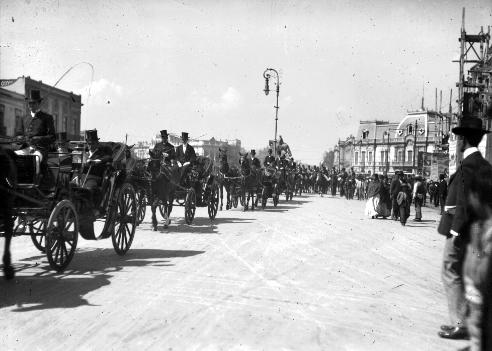 Desfile de carruajes teniendo como fondo el inicio del paseo de la Reforma.png